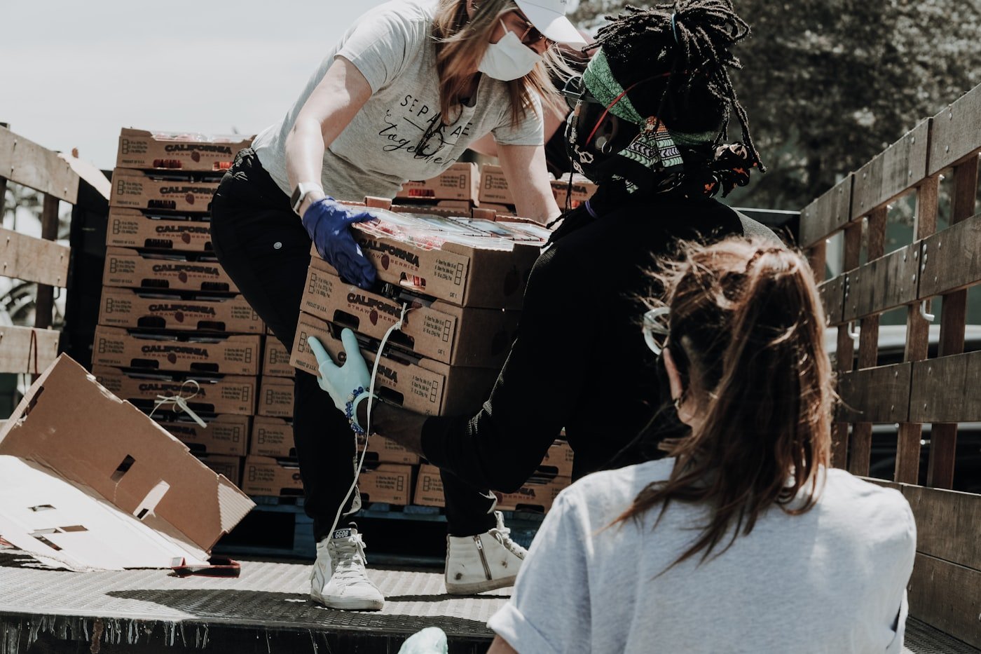 Volunteers passing boxes of fresh food from a delivery truck for community distribution