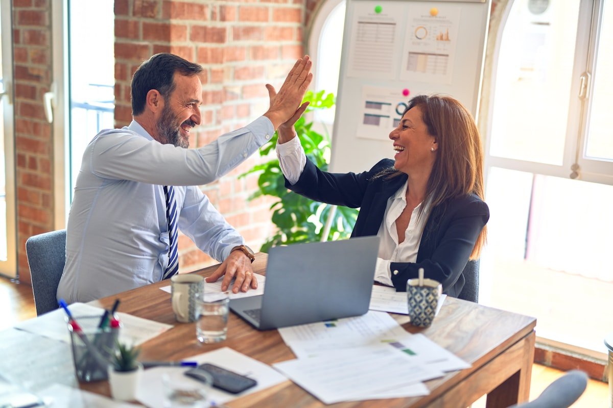 Two colleagues celebrating a successful staffing placement in a bright office