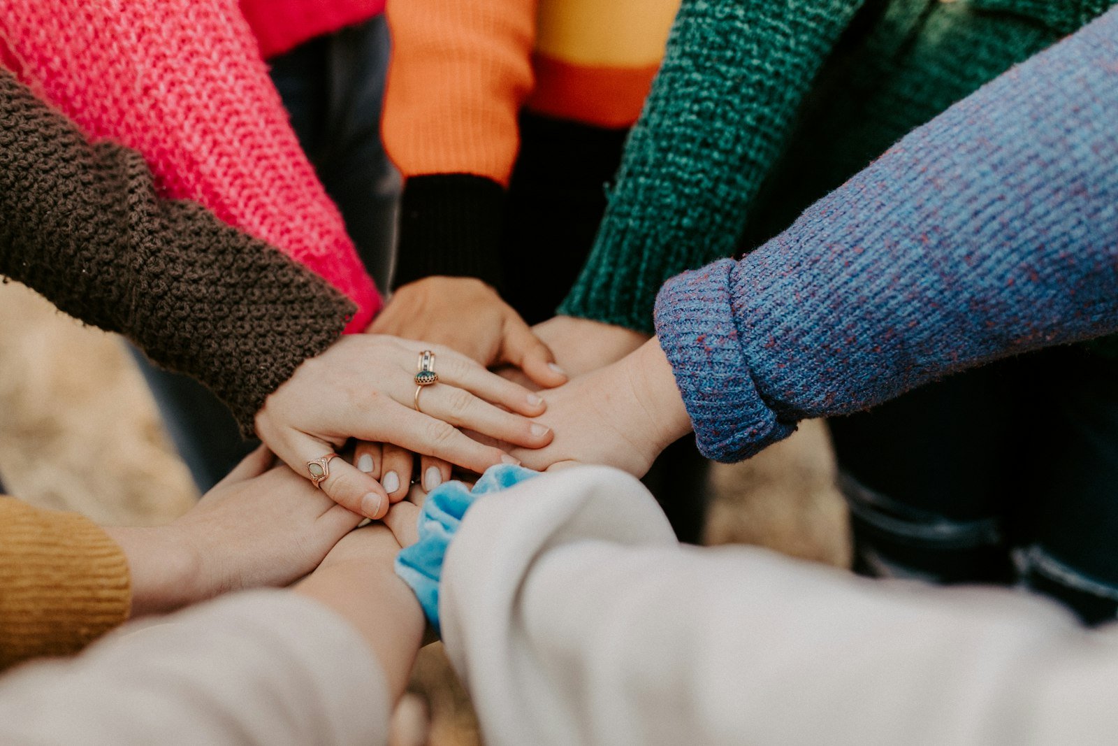 A close-knit group stacking their hands together in the middle of a circle