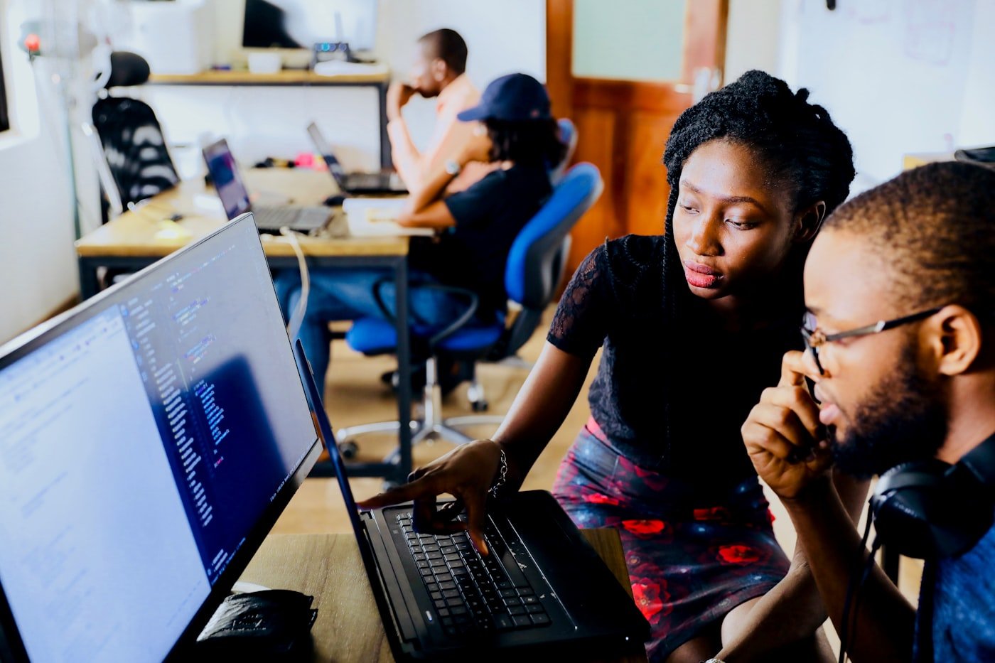 A support worker patiently guiding a young adult through a task at a desk